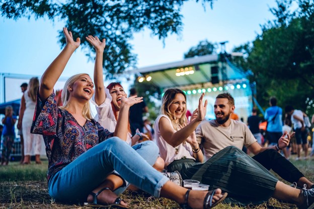 A group of people sitting on the ground with their hands up